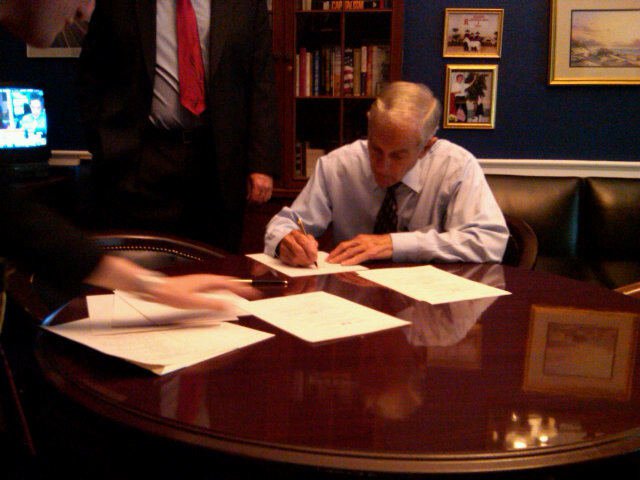 Ron Paul signs copies of the Industrial Hemp Farming Act, which is printed on hemp paper.